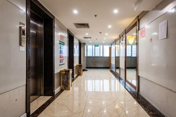 A corridor with marble flooring, an elevator, and glass doors leading to rooms. - Haotian Holiday Hotel Beijing (Beijing)