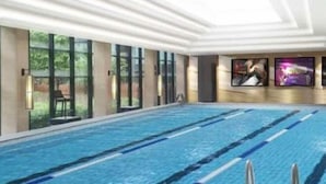 An indoor swimming pool with clear lanes, large windows, and artwork on the walls. - Haotian Holiday Hotel Beijing (Beijing)