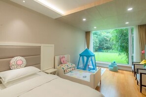 A child-friendly bedroom with a bed, a play area with a tent, and a view of a garden through a large window.
