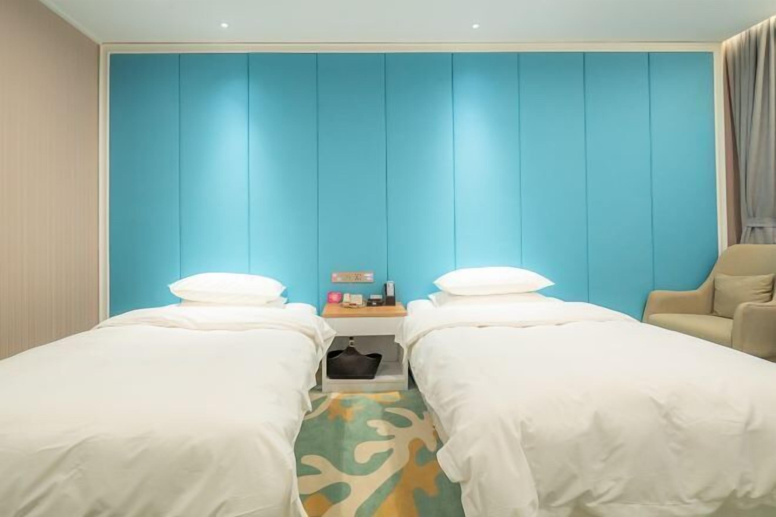 Ein Hotelzimmer mit zwei Betten, einem kleinen Tisch mit einer Lampe und einem Sessel.