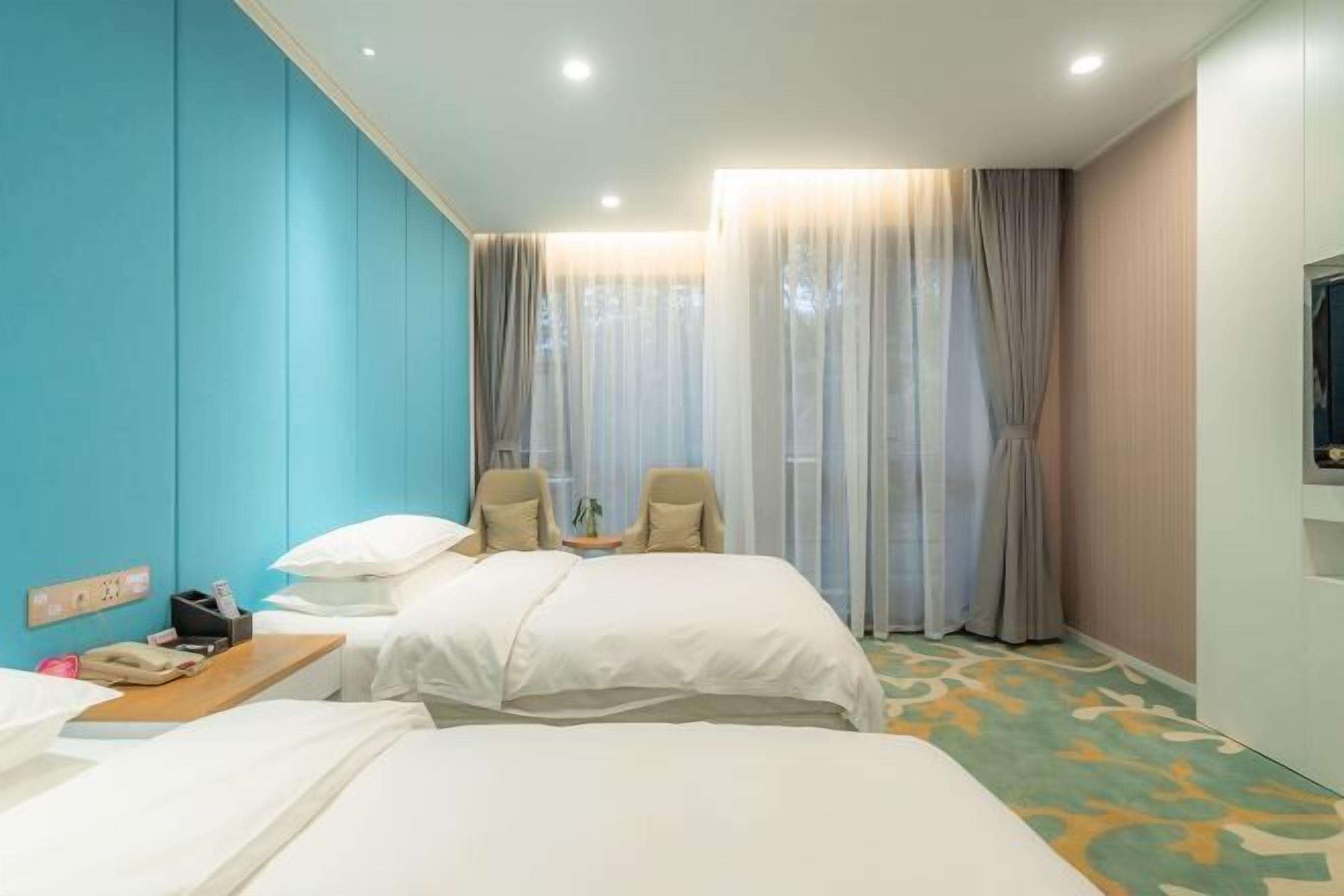 A hotel room with two beds, a desk with a phone, and a chair.