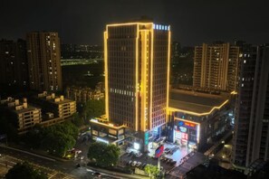 Een hoog gebouw met verlichte gevels, omringd door andere gebouwen.