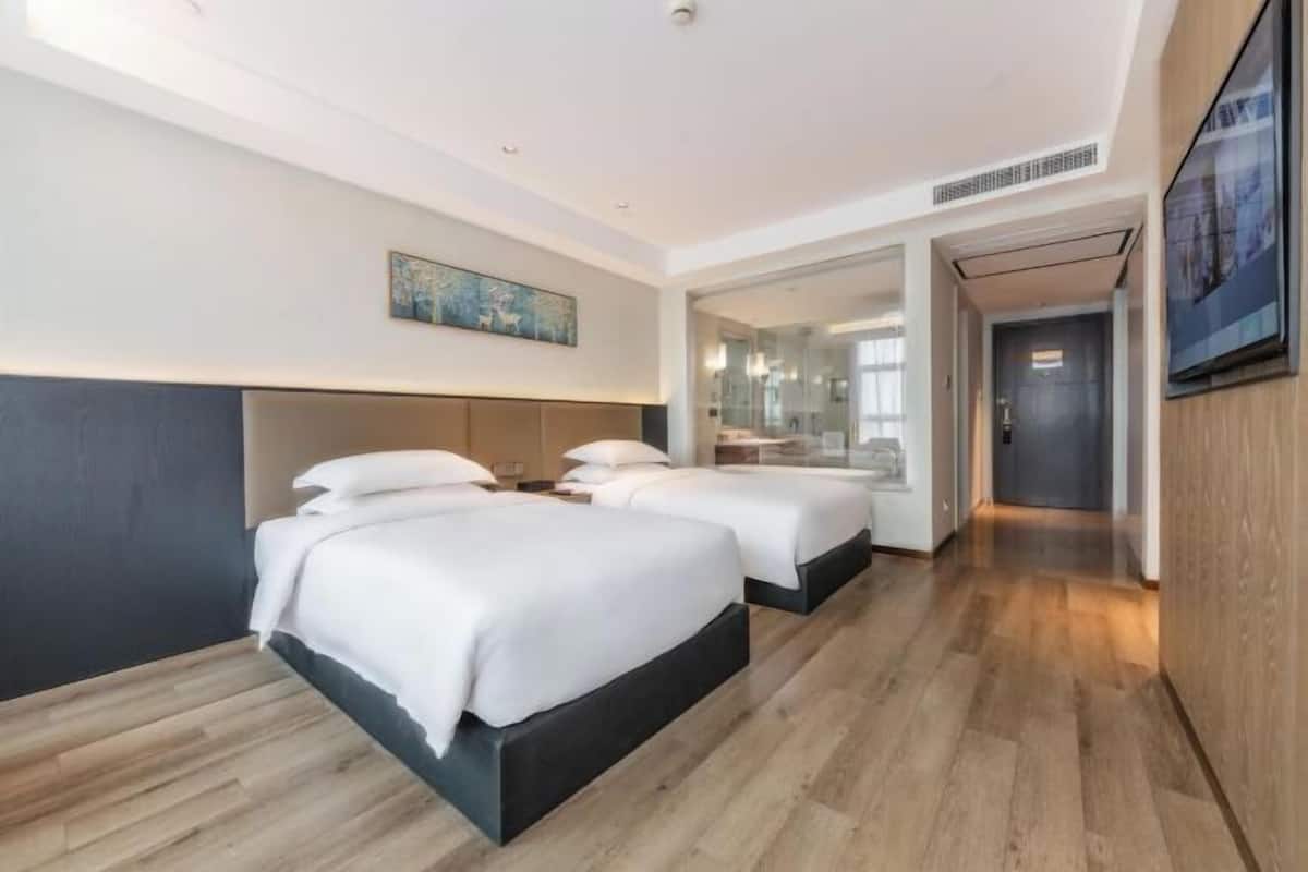 Une chambre d’hôtel avec deux lits, un grand miroir et un plancher en bois.