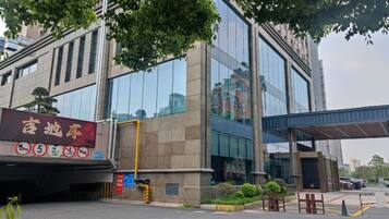 A modern building with a large glass facade, a covered entrance, and a parking area with marked spaces.