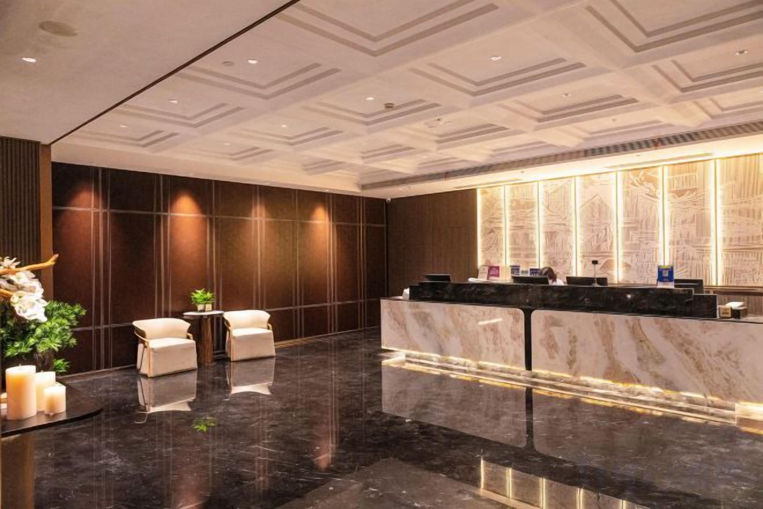 A hotel lobby with a reception desk, seating area, and a decorative plant.