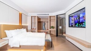 Ein modernes Hotelzimmer mit Bett, Nachttisch, Fernseher, Kleiderschrank und einer Bank.