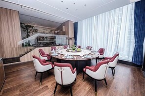 A modern dining area with a round table, multiple chairs, and a view of the kitchen and living area in the background. - Hangzhou Junhu International Hotel (HANGZHOU)