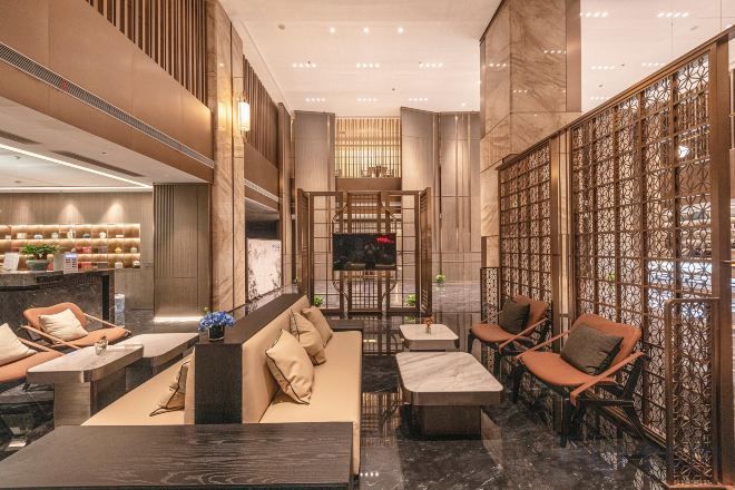 A spacious lobby with seating areas, a reception desk, and a television screen.