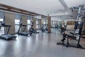 Een fitnessruimte met loopbanden, elliptische trainers en gewichtapparaten.