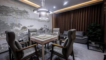 A modern room with a dining table, four chairs, a large wall mural, and a hanging light fixture.