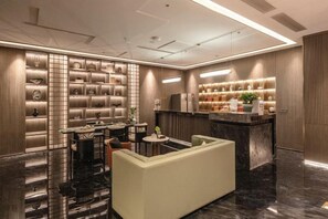 Eine moderne Hotelhalle mit einer Rezeption, einer Lounge und einer Wand mit Dekorationen.