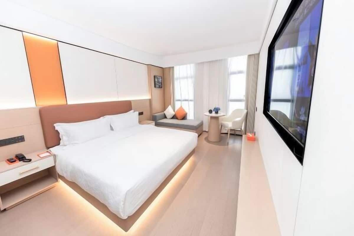 Une chambre d’hôtel moderne avec un grand lit, une table de chevet et un écran de télévision.