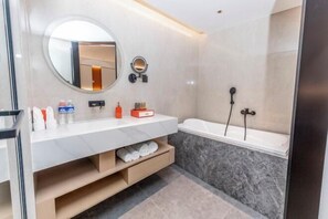 Une salle de bain moderne avec un meuble-lavabo blanc, un miroir rond, une baignoire et un espace douche.