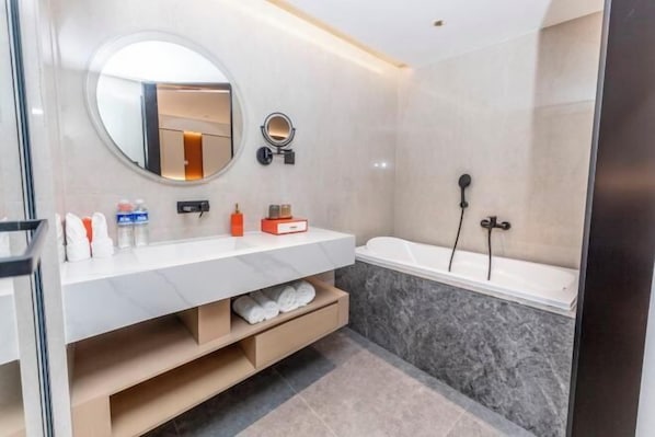 Une salle de bain moderne avec un meuble-lavabo blanc, un miroir rond, une baignoire et un espace douche.