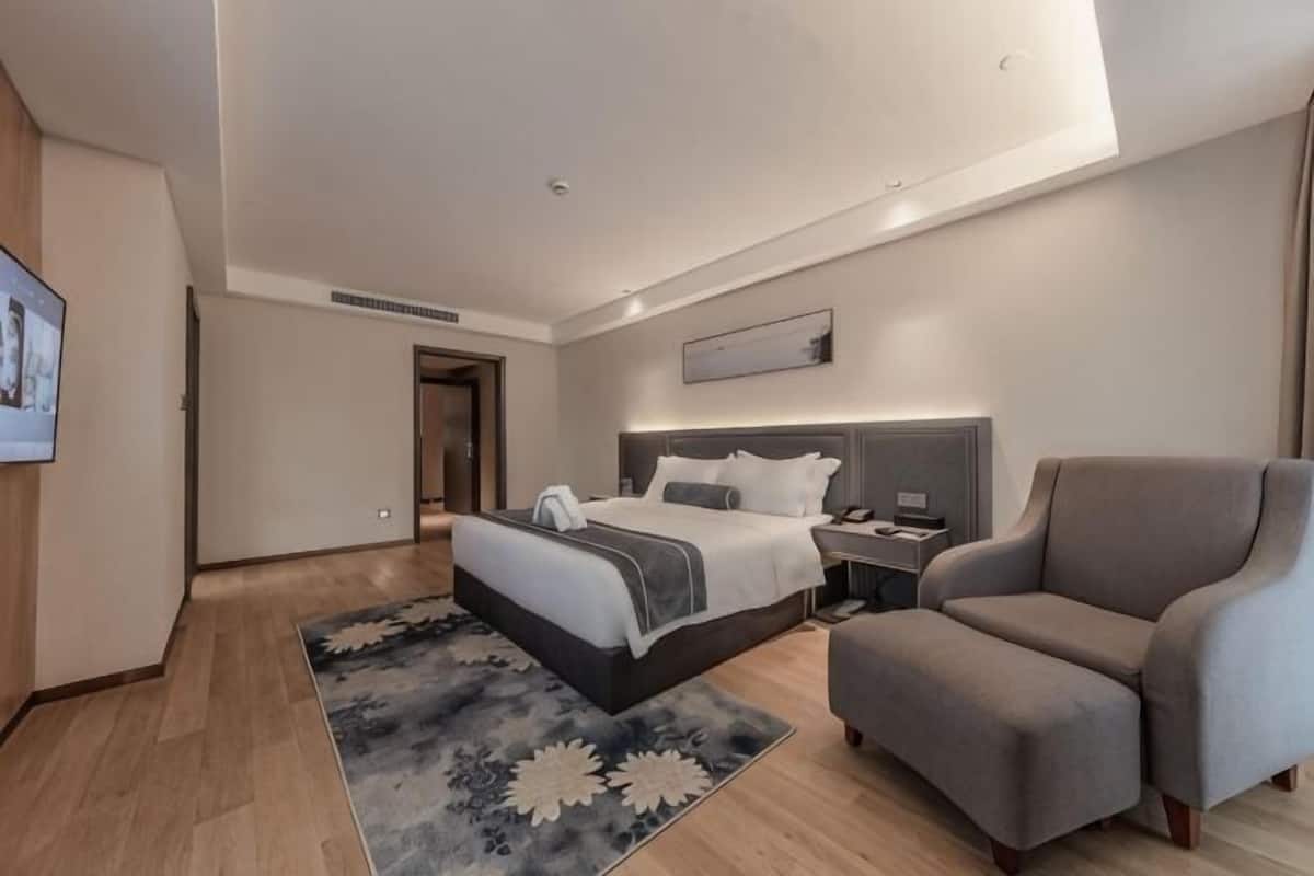 Une chambre d’hôtel moderne dotée d’un grand lit, d’un coin salon, d’un bureau et d’une télévision à écran plat.