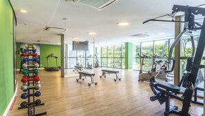 Un gimnasio con equipo de ejercicio, ventanas amplias y piso de madera.
