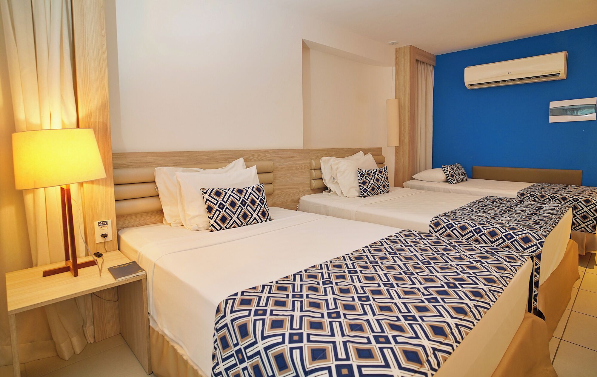 Habitación de hotel con dos camas, un escritorio, una lámpara y un equipo de aire acondicionado.