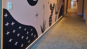 Un pasillo con un mural que muestra una luna creciente, estrellas y cactus.
