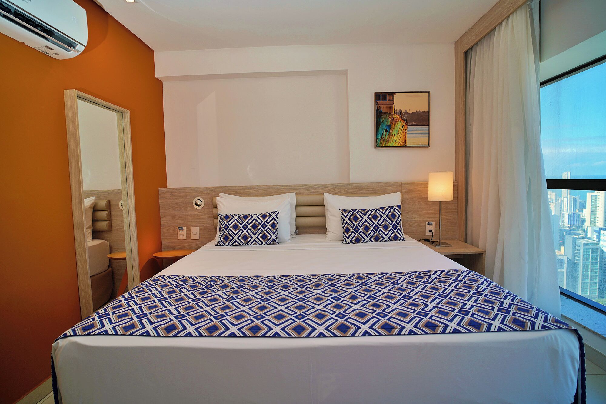 Una habitación de hotel con una cama grande, una mesita de noche, una lámpara y un cuadro en la pared.