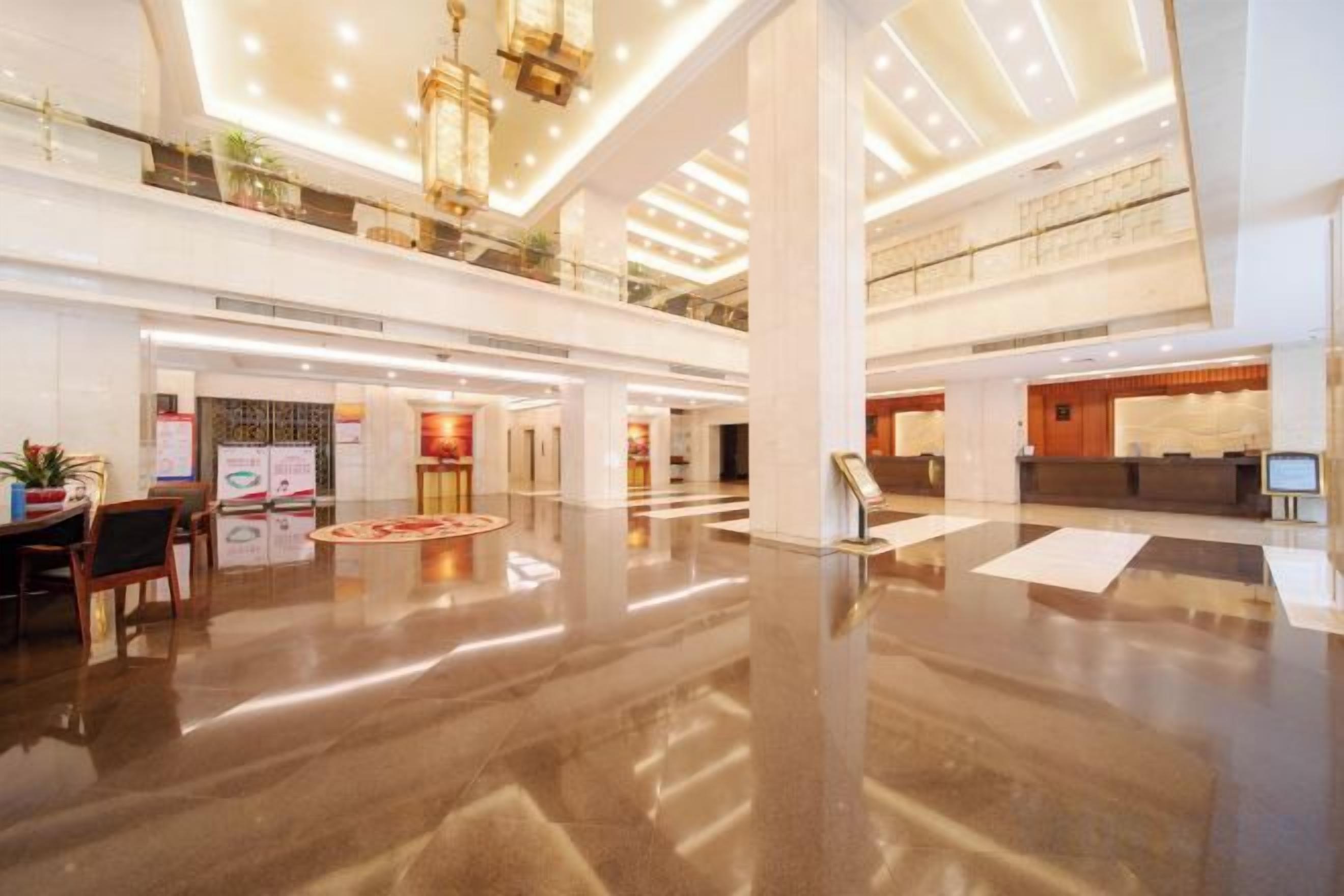 A spacious lobby with a high ceiling, polished floors, and a reception desk.