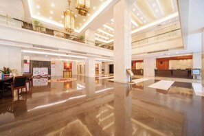Un'ampia hall con soffitto alto, pavimenti lucidi e una reception.