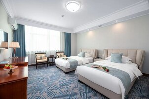 Habitación de hotel con dos camas, un escritorio, una silla y un ventanal grande.