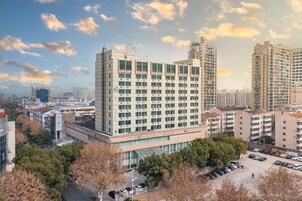 Un edificio de gran altura con varios pisos, rodeado de otros edificios y árboles.