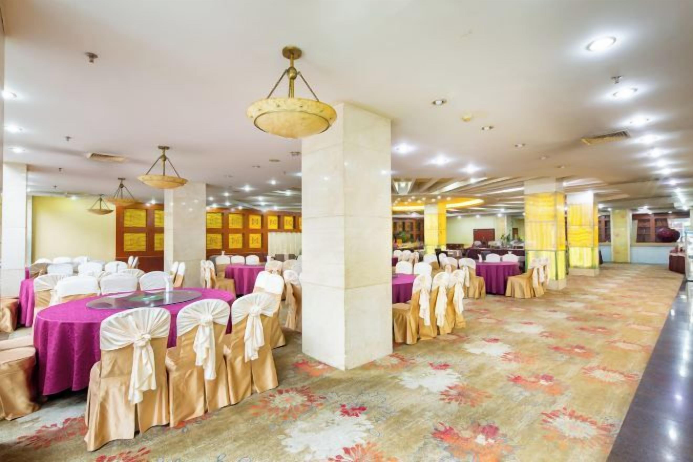 A banquet hall with tables set for events, featuring a patterned carpet and ceiling lights.