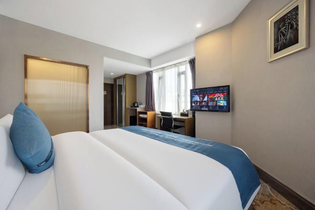 Una habitación de hotel con cama, escritorio, televisor y puerta.