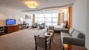Ein Hotelzimmer mit Fernseher, Sitzgelegenheit und großen Fenstern.