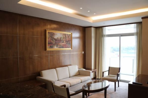 En moderne hotellobby med sofa, stole, sofabord, et billede og et stort vindue.