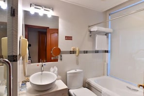 Et badeværelse med vask, toilet og badekar.