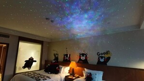 Ein Hotelzimmer mit zwei Betten, einem Nachttisch mit Lampe sowie einer Wand mit Bär-Dekorationen.
