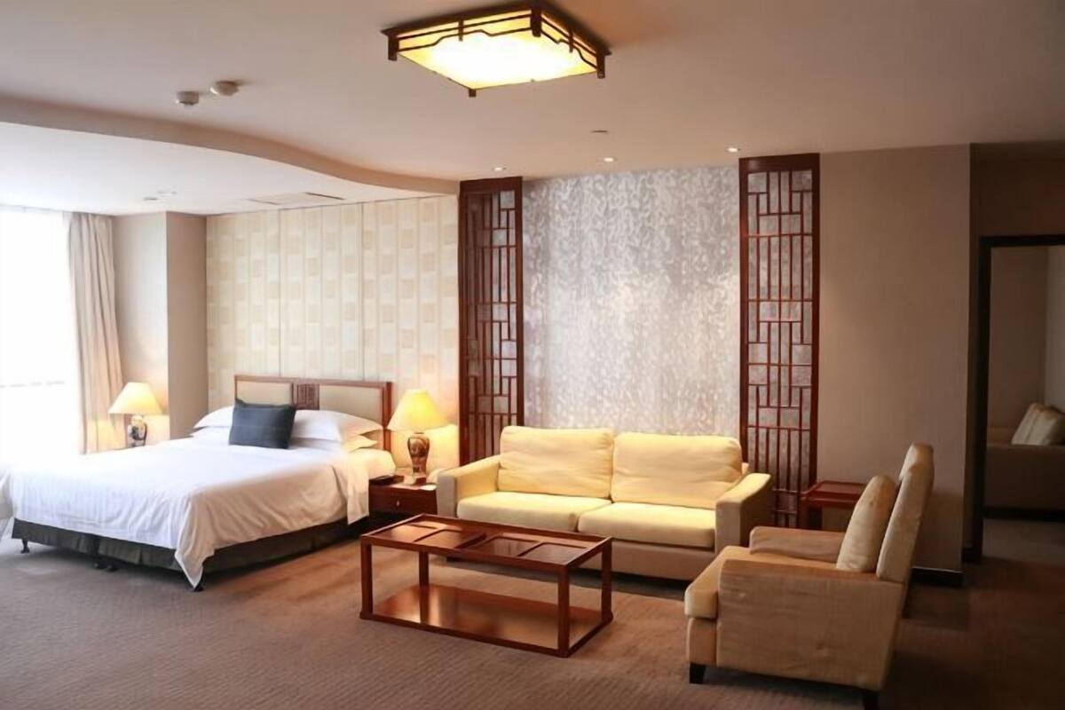 Una habitación de hotel con una cama, un sofá, una mesa de centro y una silla.