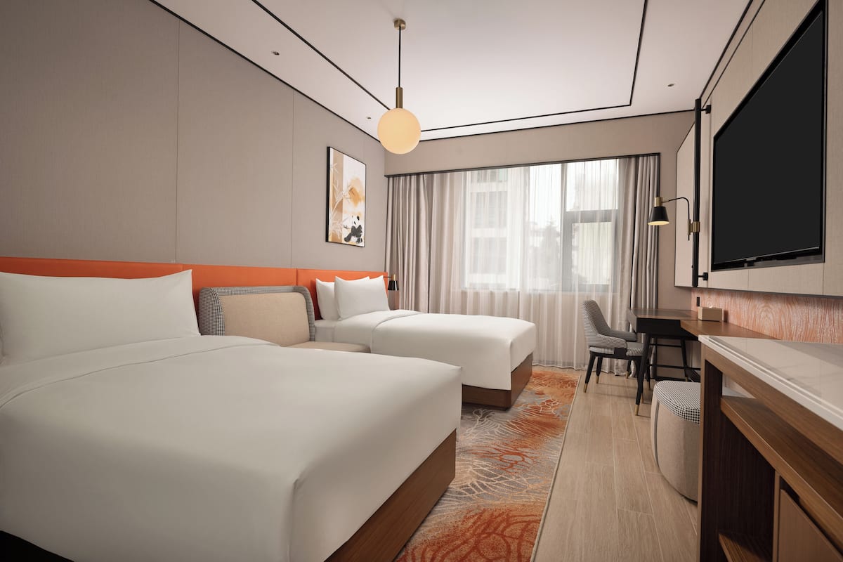 Habitación de hotel con una cama grande, un escritorio y una televisión.