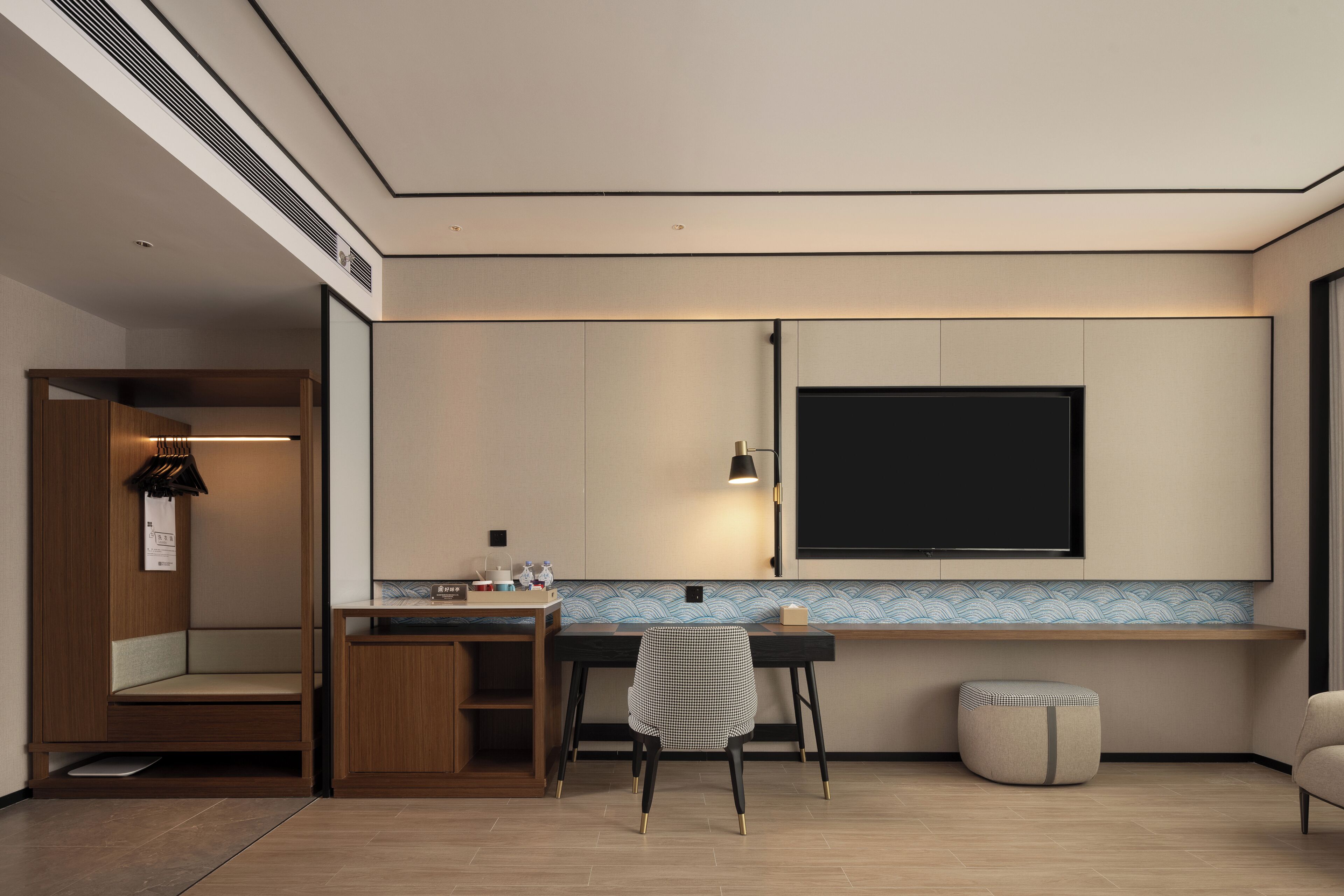 Een moderne kamer met een houten bankje, een bureau, een stoel en een televisie.