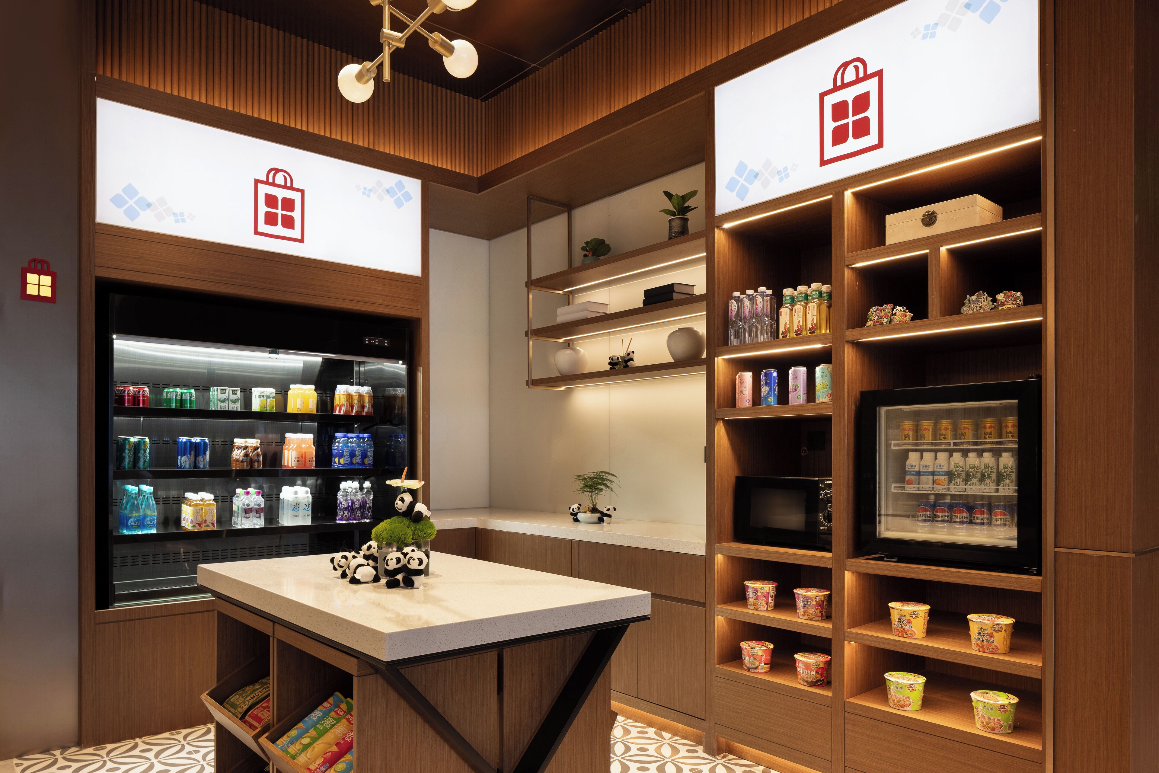 A modern hotel lobby with a central counter, shelves with beverages, and panda decorations.