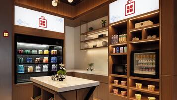 A modern hotel lobby with a central counter, shelves with beverages, and panda decorations.