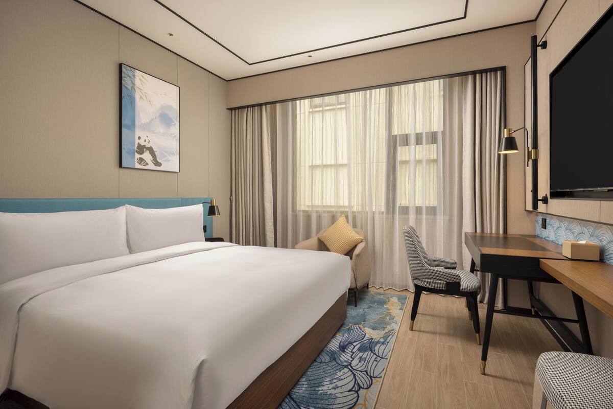 Una habitación de hotel con una cama grande, un escritorio, una silla y un televisor.