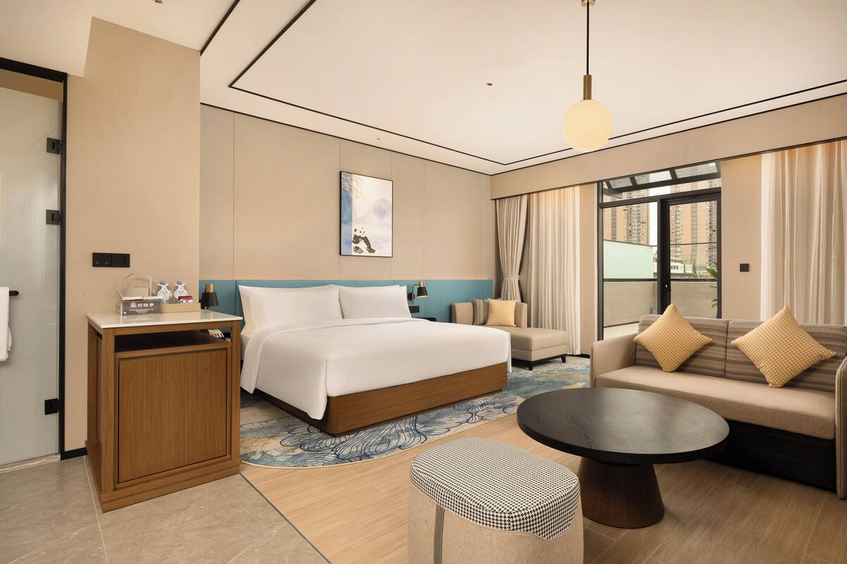Una habitación de hotel con una cama grande, un sofá, una mesa de centro y un escritorio.