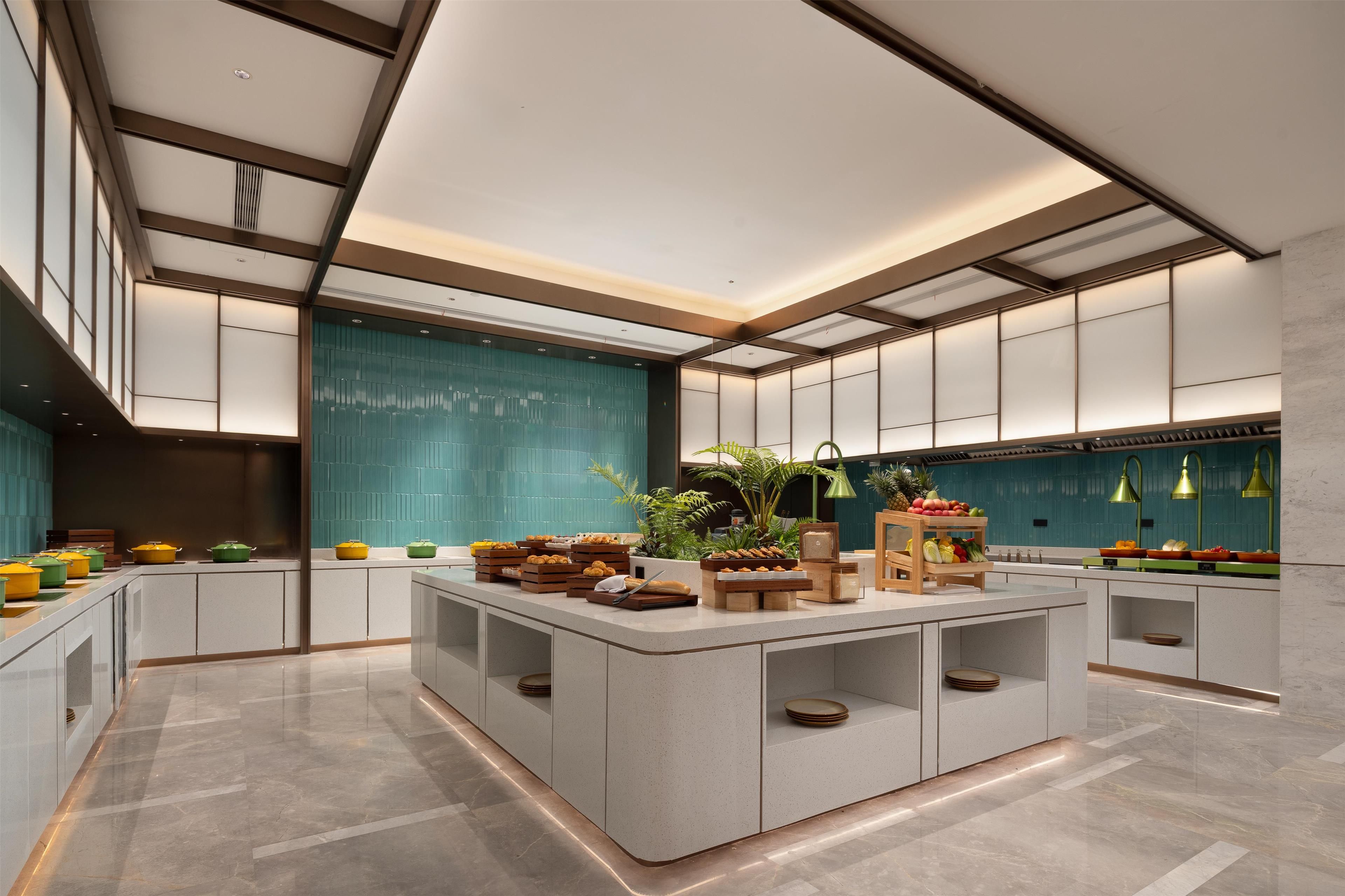 A modern kitchen with a central island, built-in appliances, and a teal backsplash.
