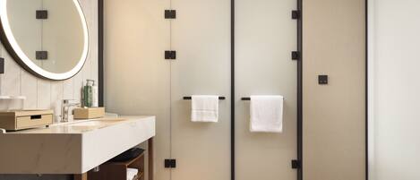 A modern bathroom with a large mirror, a sink, and two towel racks.