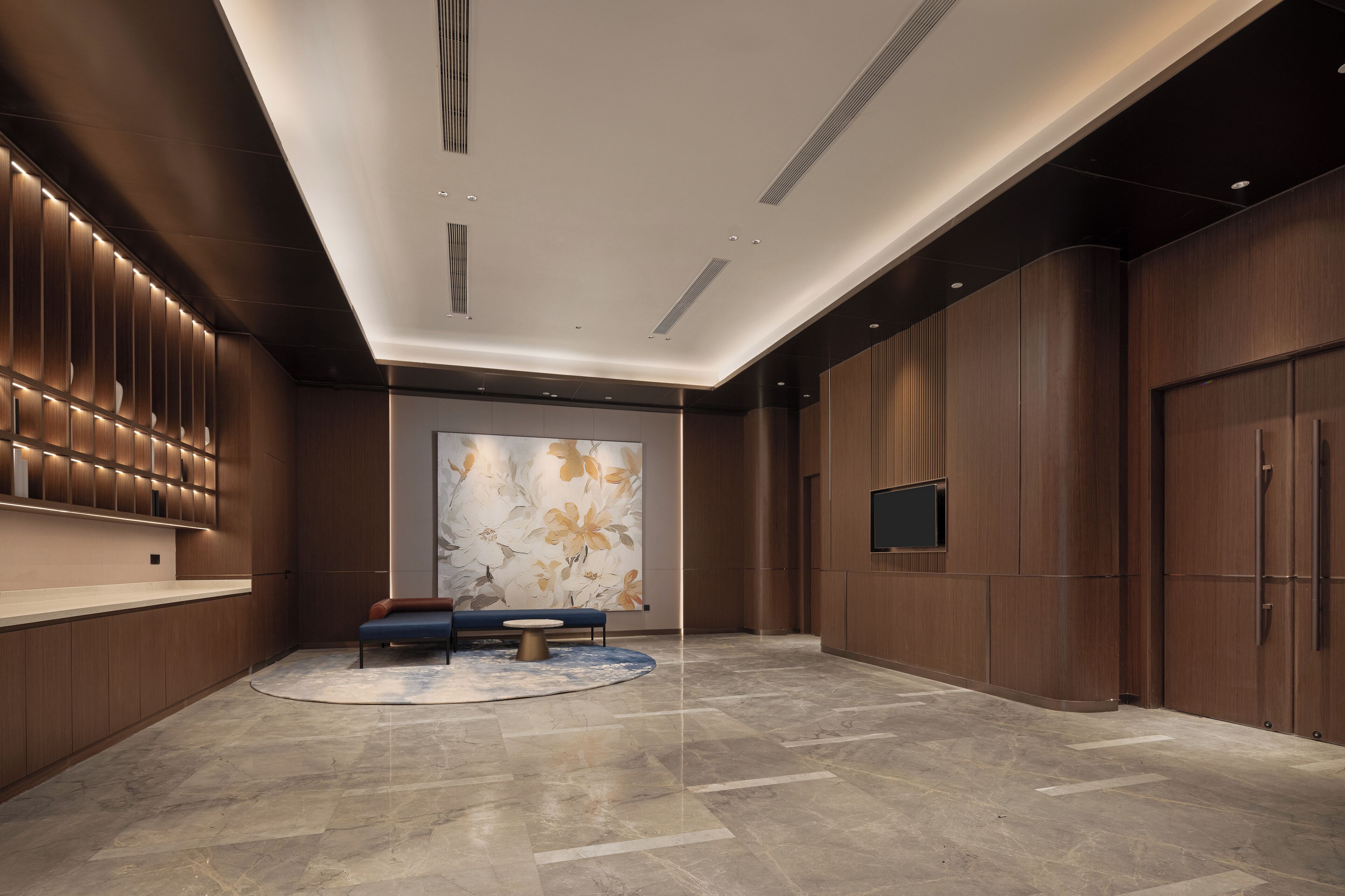 A modern lobby with a reception desk, seating area, and a large decorative wall.