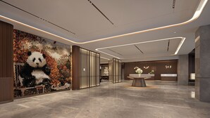 Un hall d’entrée moderne avec un comptoir d’accueil, une grande fresque représentant un panda et un sol en marbre.