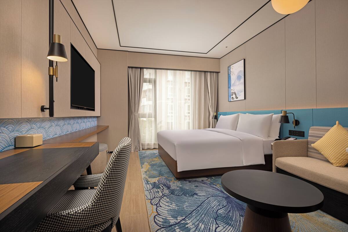 Una habitación de hotel con cama, sofá, escritorio y silla.