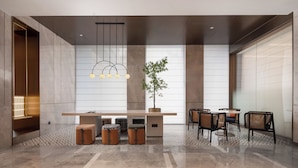Een moderne lobby met een lange receptiebalie, een zithoek en een groot raam dat voor natuurlijk licht zorgt.