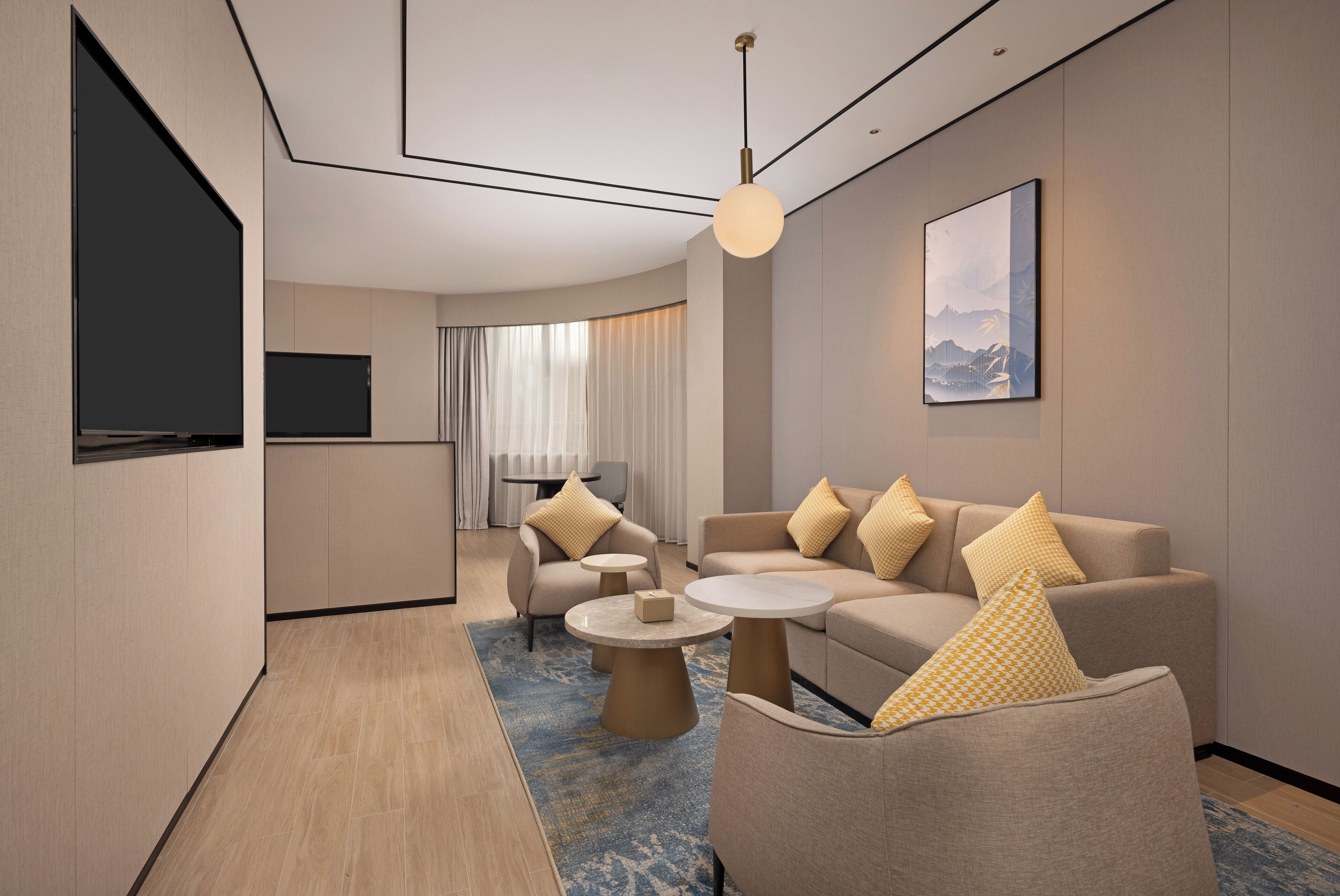 Een moderne hotelkamer met een zithoek, een televisie, een bijzettafeltje en een schilderij aan de muur.