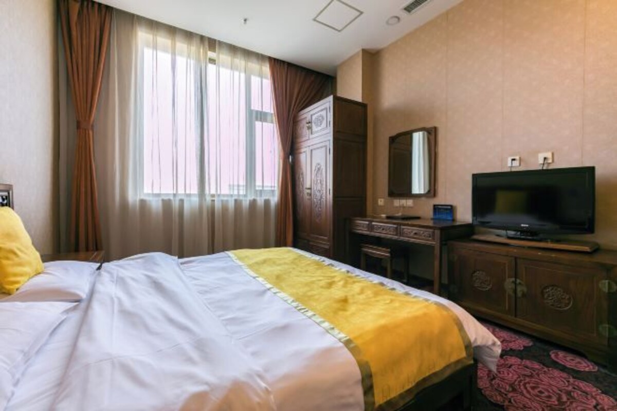 Une chambre d’hôtel équipée d’un lit, d’une télévision, d’un bureau et d’une armoire.