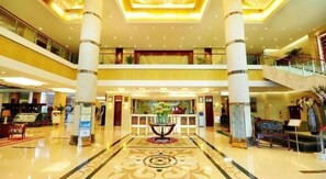 A spacious lobby with a central reception desk, multiple floors, and a grand staircase. - Chengyang Detai Hotel (Qingdao)