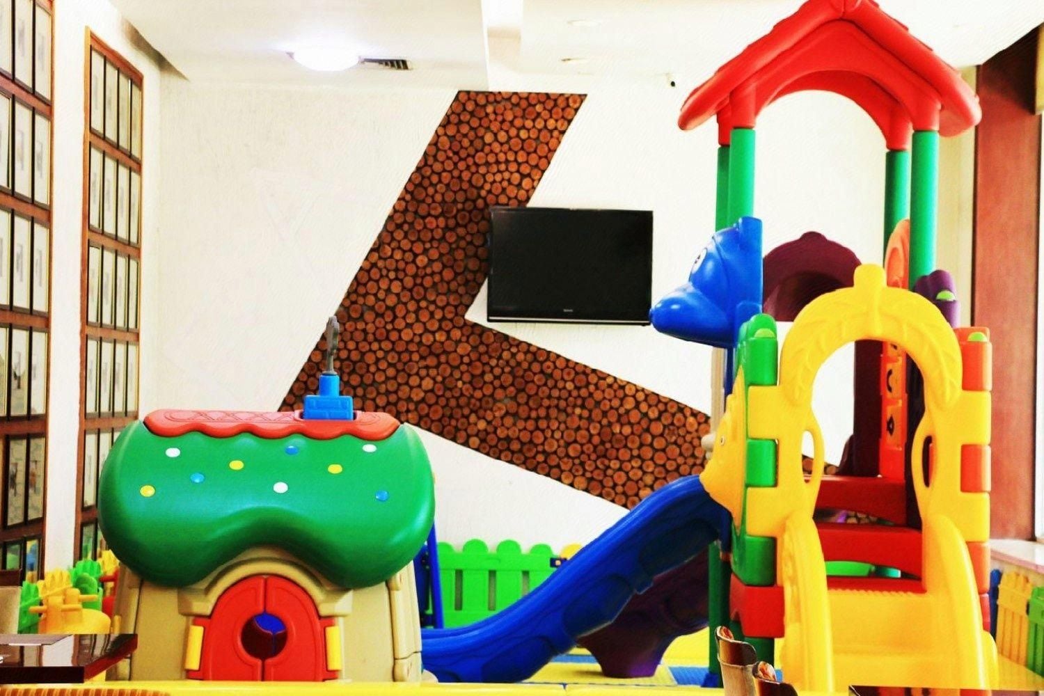 A children's play area with a slide, a climbing structure, and a small house.
